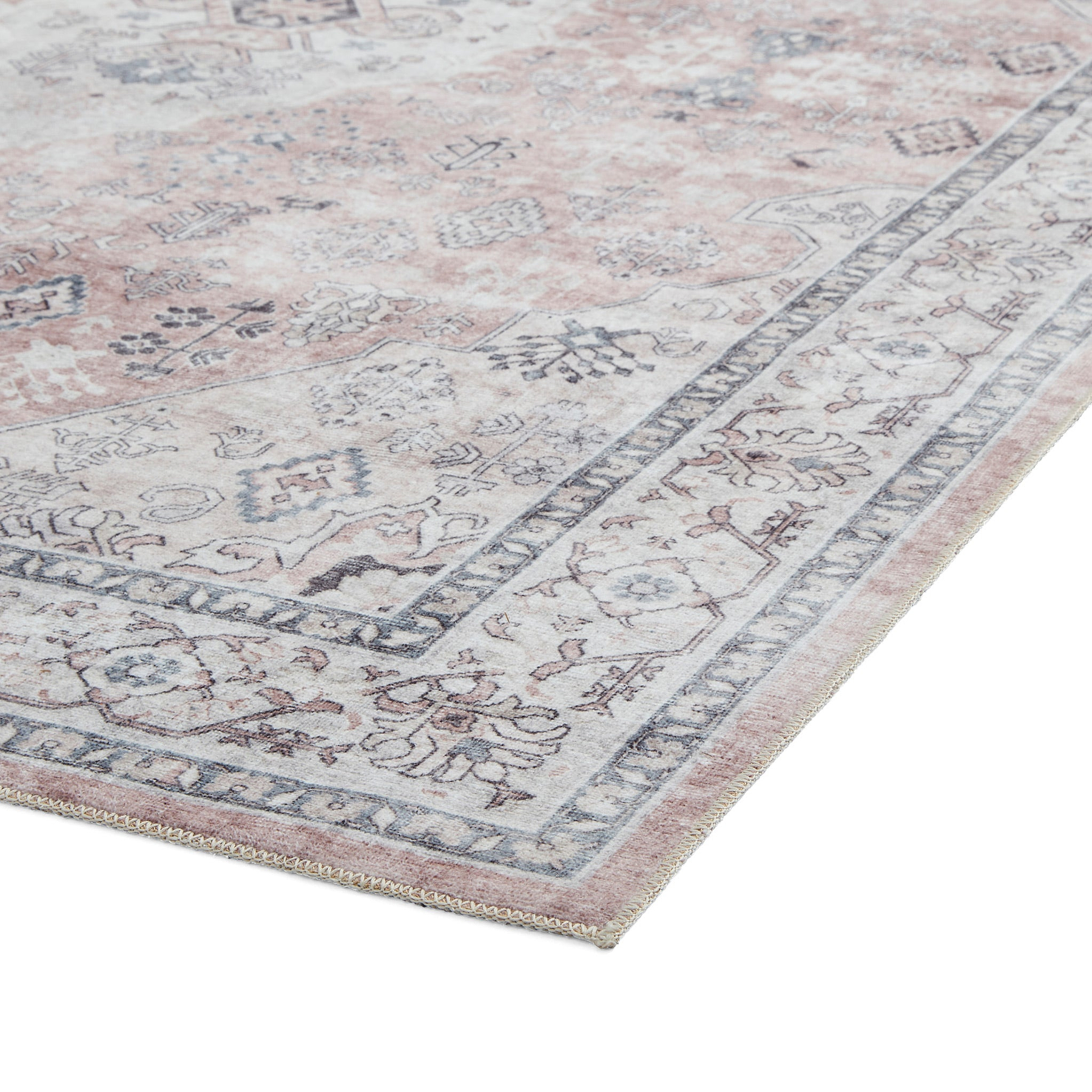A detailed, vintage-style rug with a distressed pink and gray pattern lies flat on a white background.