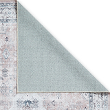A patterned rug partially overlaps with a plain rug, creating a diagonal line of contrast, on a simple white background.