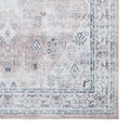A patterned rug with geometric and floral designs rests flat, showcasing muted tones mainly in the grey and pale pink spectrum, creating a vintage aesthetic.
