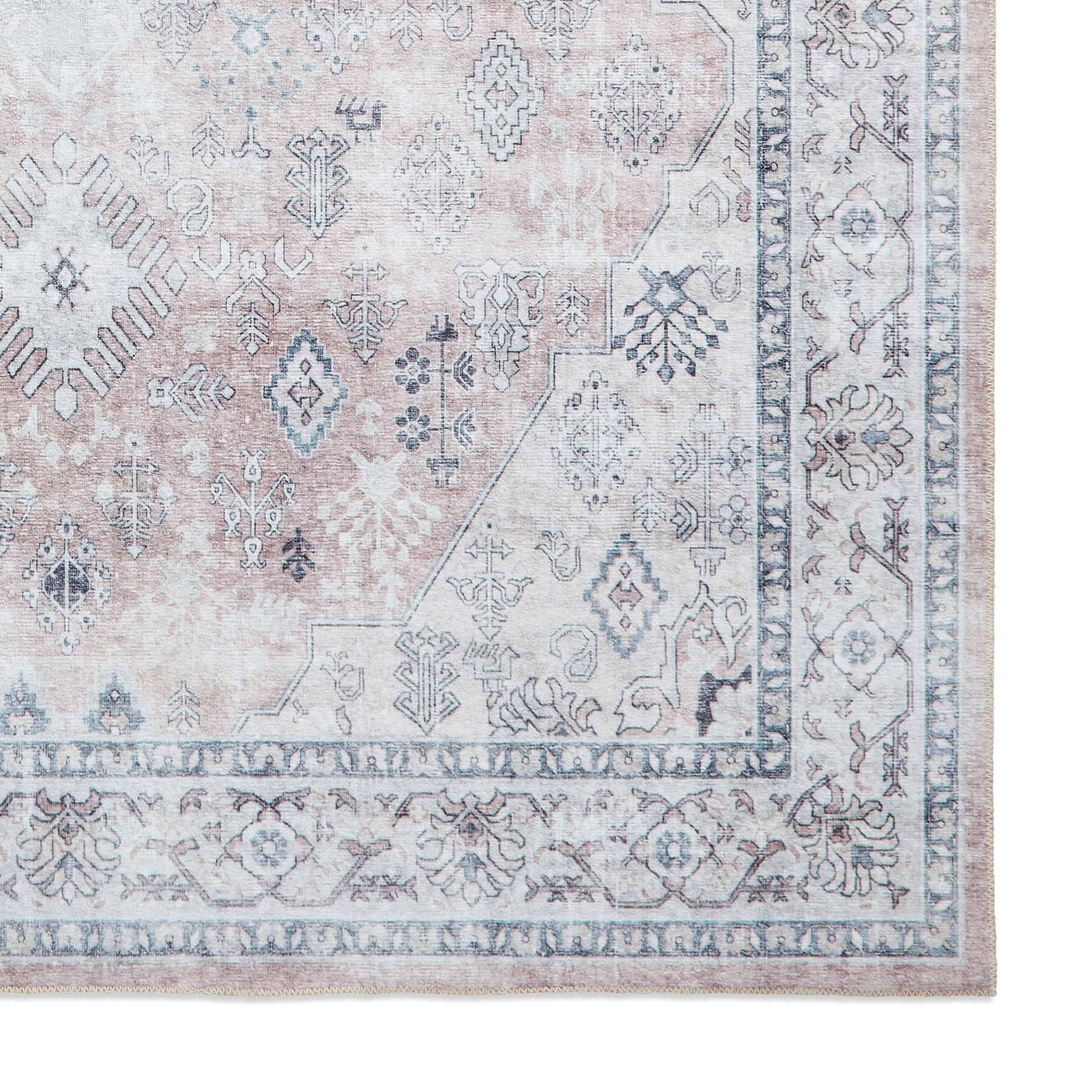 A patterned rug with geometric and floral designs rests flat, showcasing muted tones mainly in the grey and pale pink spectrum, creating a vintage aesthetic.