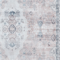 A patterned rug exhibits intricate designs with varied shapes and symbols in muted blues and beiges, emphasizing traditional textile art.