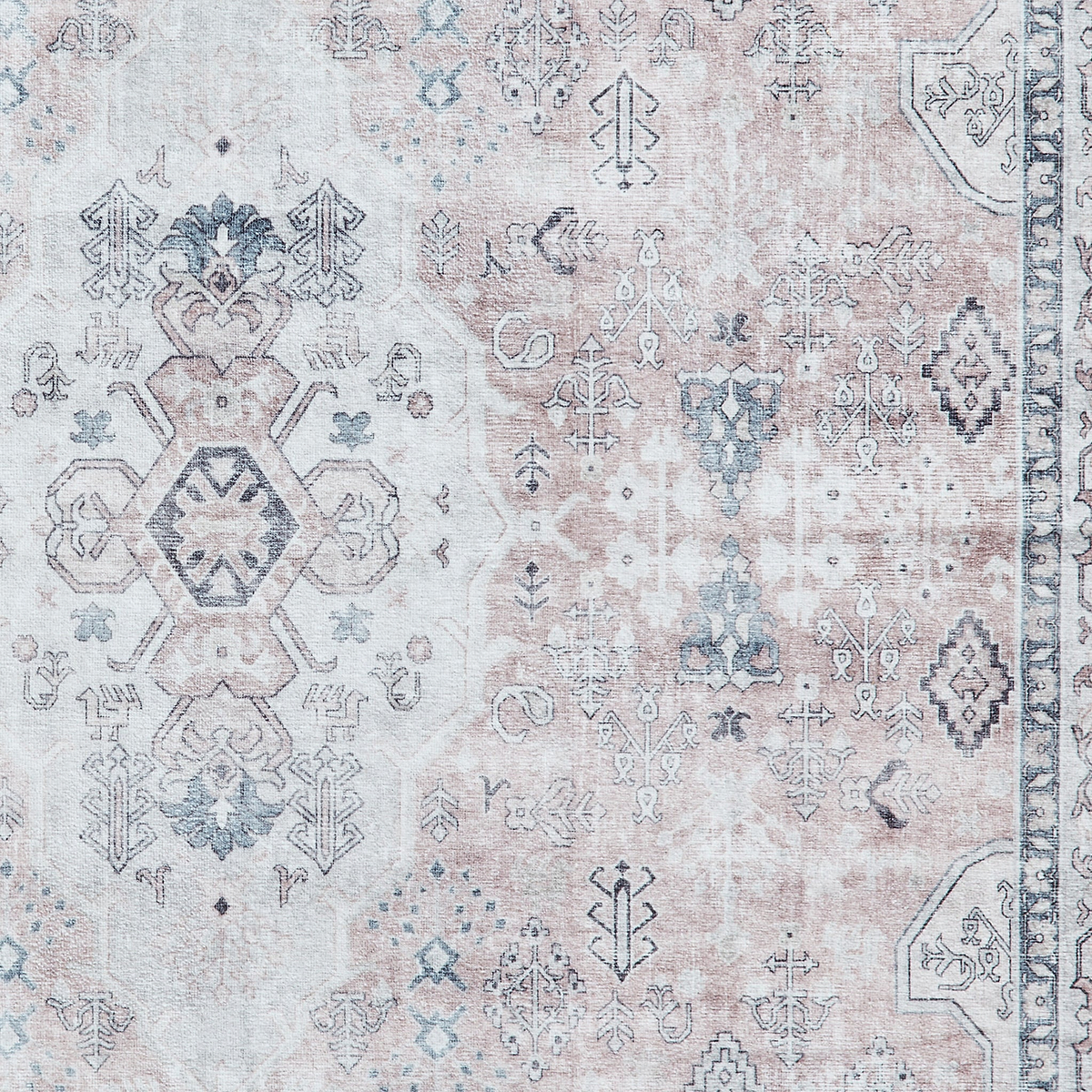 A patterned rug exhibits intricate designs with varied shapes and symbols in muted blues and beiges, emphasizing traditional textile art.