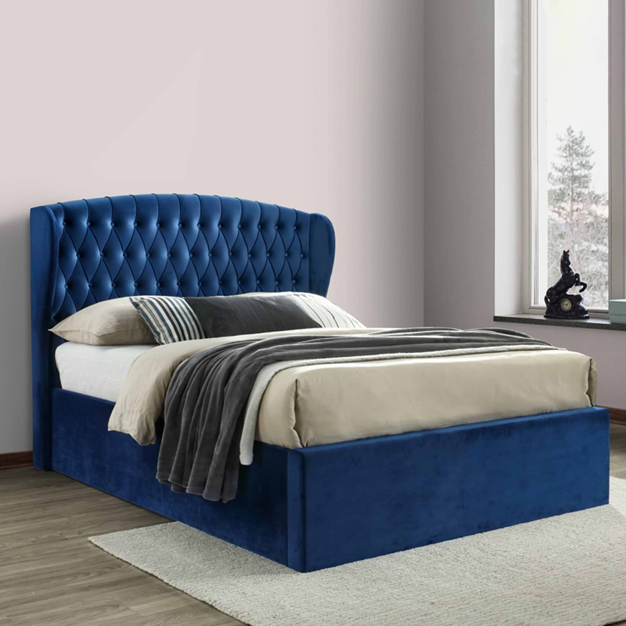 A blue, tufted headboard attached to a matching bed base with a white, quilted mattress in an elegant room with paneled walls and herringbone-patterned wooden floor.