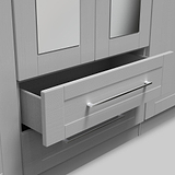 A partial view of a white cabinet with one drawer partially open, revealing its dark interior, set against a light grey background.