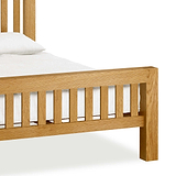 A wooden bed with a white pillow and bedding, set against a white background.
