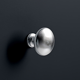 A silver doorknob protrudes from a dark grey surface, casting a soft shadow to the right. There is a minimalistic and clean aesthetic.