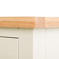 A wooden plank is shown with a patch of sandpaper on its surface, indicating sanding in progress, placed above a cream-colored drawer.
