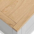 Wooden table corner with visible grain, overhanging a blurred white background.