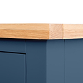 A wooden plank with its corner covered by a piece of sandpaper, set against a blue furniture backdrop.