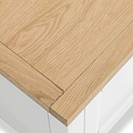 Light wooden tabletop with a visible corner, showcasing its grain and texture, positioned above a blurred white background.