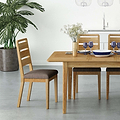 A wooden dining table set with blue dishes and glasses, flanked by chairs, in a room with a potted plant and pendant lights. The scene conveys a modern, minimalist aesthetic.
