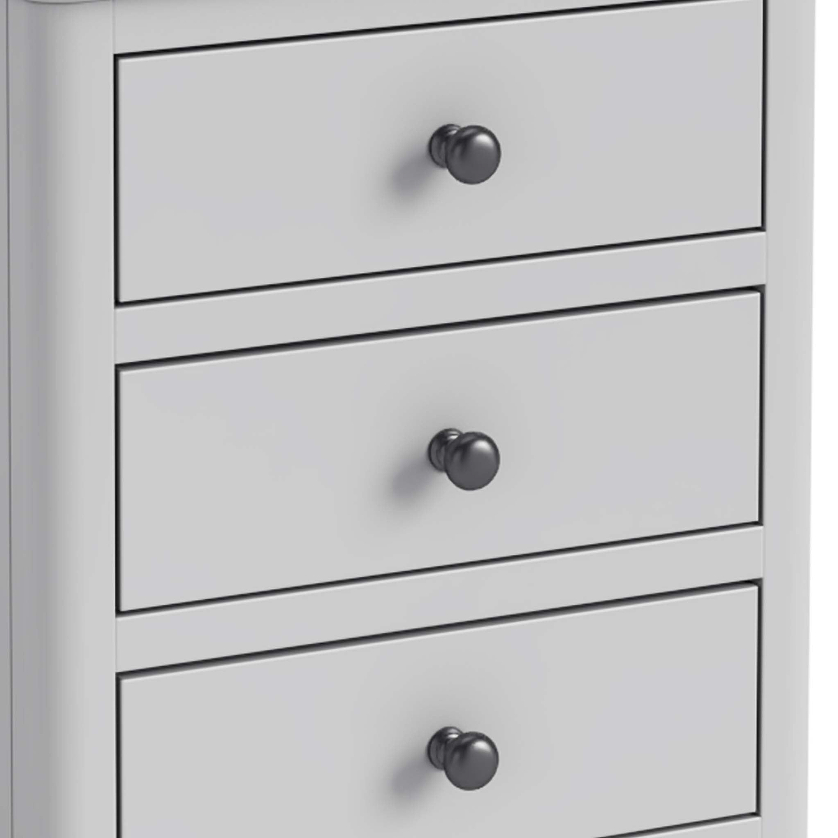 A white chest of drawers with three closed drawers, each featuring a round, black knob, set against a plain background.