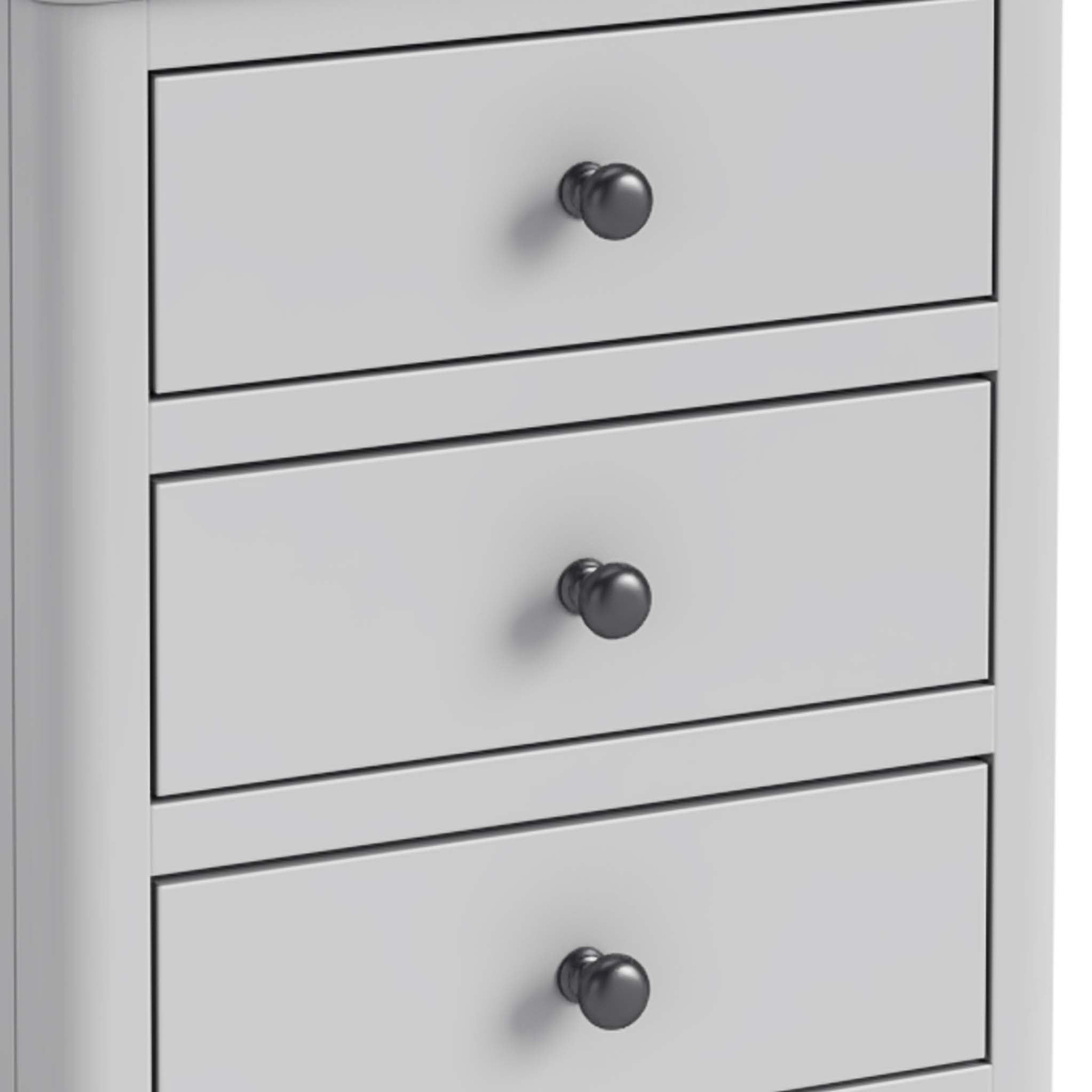 A white chest of drawers with three closed drawers, each featuring a round, black knob, set against a plain background.