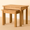 A pair of nested wooden tables, the smaller one partially slid beneath the larger, against a neutral-toned backdrop.