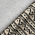 A gray plush towel rests on patterned fabric with abstract black designs, creating a contrast of textures.
