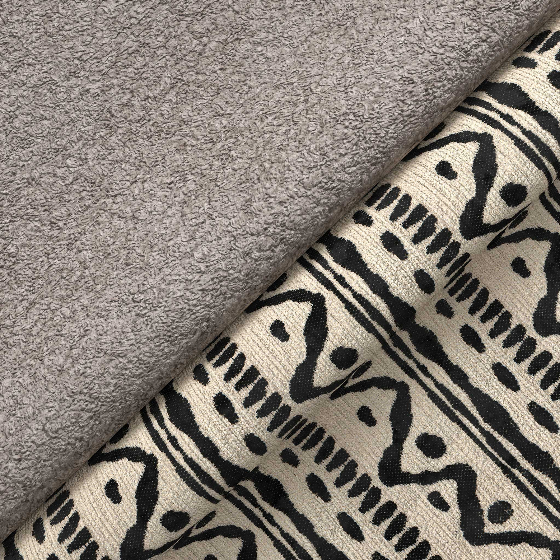 A grey fluffy towel overlaps a patterned fabric with geometric black designs on a beige background, suggesting a home decor setting.