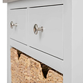 A white chest of drawers with metallic knobs, one drawer slightly open revealing a straw basket inside.