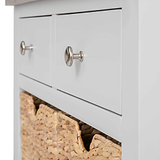 A white chest of drawers with metallic knobs, one drawer slightly open revealing a straw basket inside.