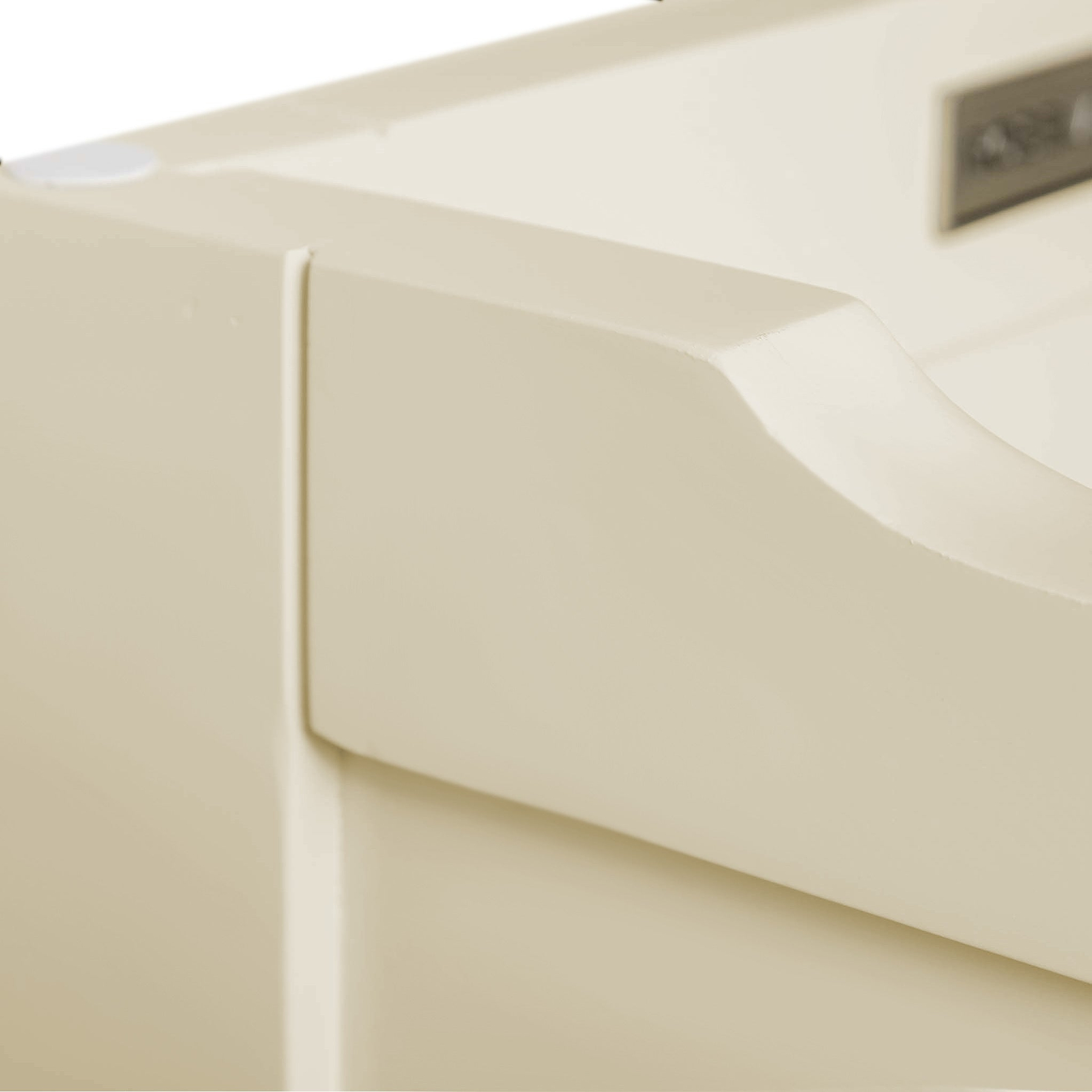 A close-up of a beige object with smooth curves and a rectangular label or emblem, possibly a part of plastic machinery or equipment, against a neutral background.