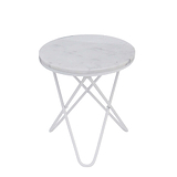 A round marble-top table with a white, crossed metal base stands idle against a white background.