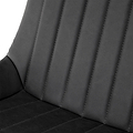 A close-up view of a black, faux-leather car seat with stitched vertical lines, against a nondescript background.