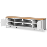 A long, low white TV stand with a light wood top has multiple compartments and two closed drawers, one open, isolated on a white background.