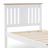 A white wooden bed frame, partially visible, with vertical slats on the headboard and wooden slats for support, against a plain white background.