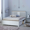 A neatly made white bed with pillows, placed in a room with decorative heart motifs on the wall and soft-toned furnishings.