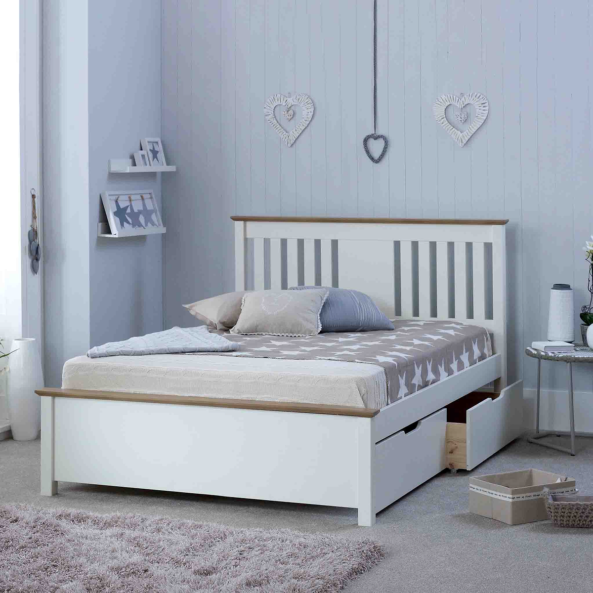 A neatly made white bed with pillows, placed in a room with decorative heart motifs on the wall and soft-toned furnishings.