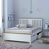 A neatly made white bed with pillows, placed in a room with decorative heart motifs on the wall and soft-toned furnishings.