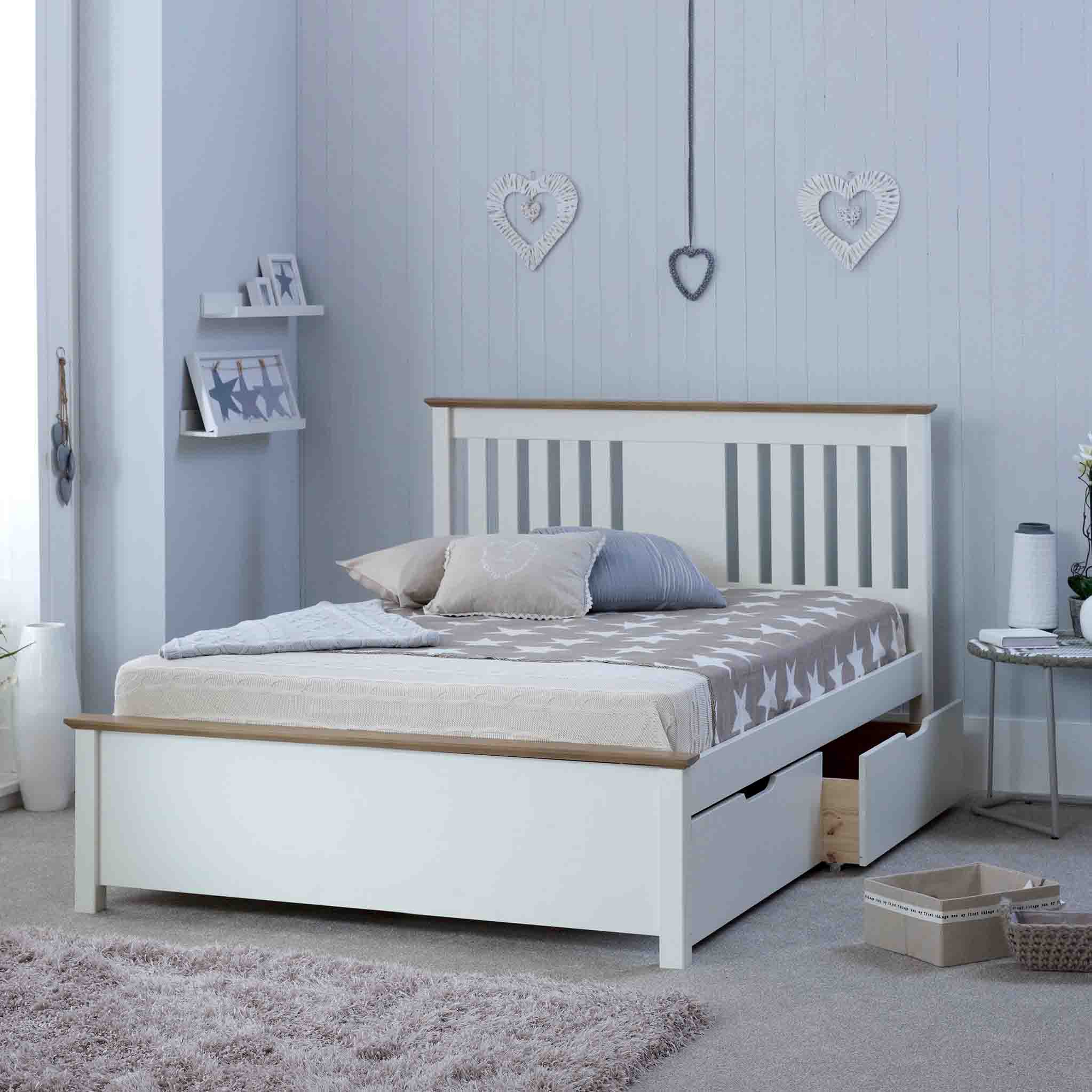 A neatly made white bed with pillows, placed in a room with decorative heart motifs on the wall and soft-toned furnishings.