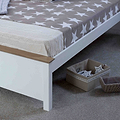 A neatly-made bed with a star-patterned blanket and a knitted throw at the foot, situated in a tidy room. A cardboard storage box rests on the floor by the bed.
