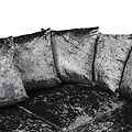 Three velvet cushions resting against each other on a matching dark, textured couch. The image is in grayscale.
