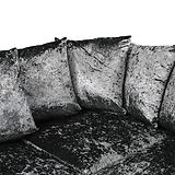 Three velvet cushions resting against each other on a matching dark, textured couch. The image is in grayscale.