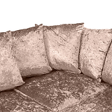 A plush corner sofa with velvety cushions, arranged neatly, in a sepia-toned image.