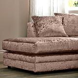 A plush crushed velvet sofa with cushions rests stationary in a cozy room with sheer curtains and a sunlit window behind it.