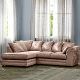 A plush pink sectional sofa sits in a room with sheer curtains, hardwood floor, and a blue wall.