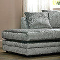 A grey crushed velvet loveseat with plush cushions is positioned in a well-lit room with sheer curtains.
