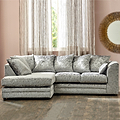 A plush L-shaped sectional sofa sits prominently, with patterned cushions, in a room featuring sheer curtains, a large round mirror, and hardwood flooring.