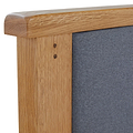 A wooden frame with visible grain details borders a textured grey fabric, suggesting a piece of furniture or a pinboard.