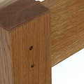 A close-up of a wooden structure with a vertical post intersecting a horizontal beam, showing two visible nail or screw heads for joining.