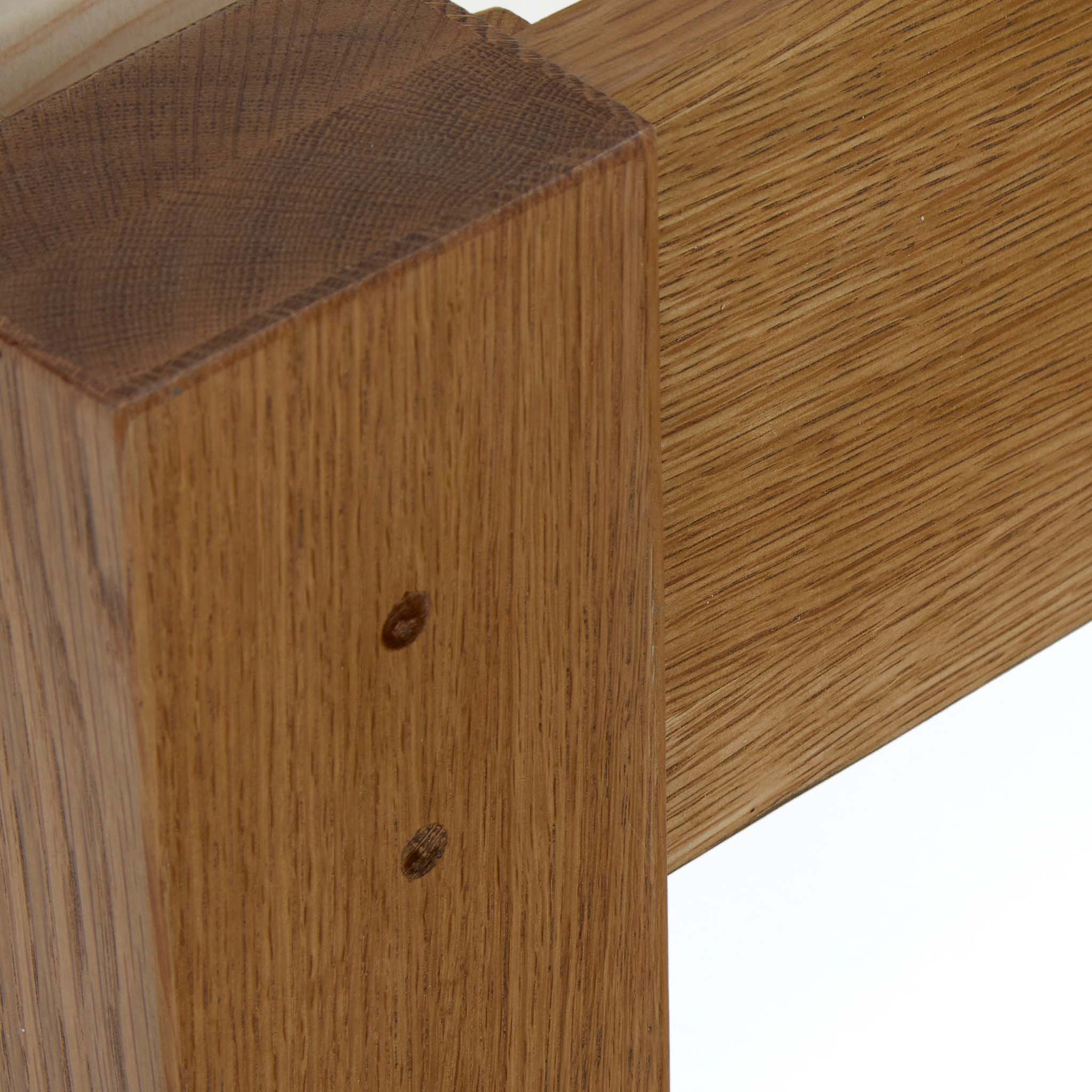 A close-up of a wooden structure with a vertical post intersecting a horizontal beam, showing two visible nail or screw heads for joining.