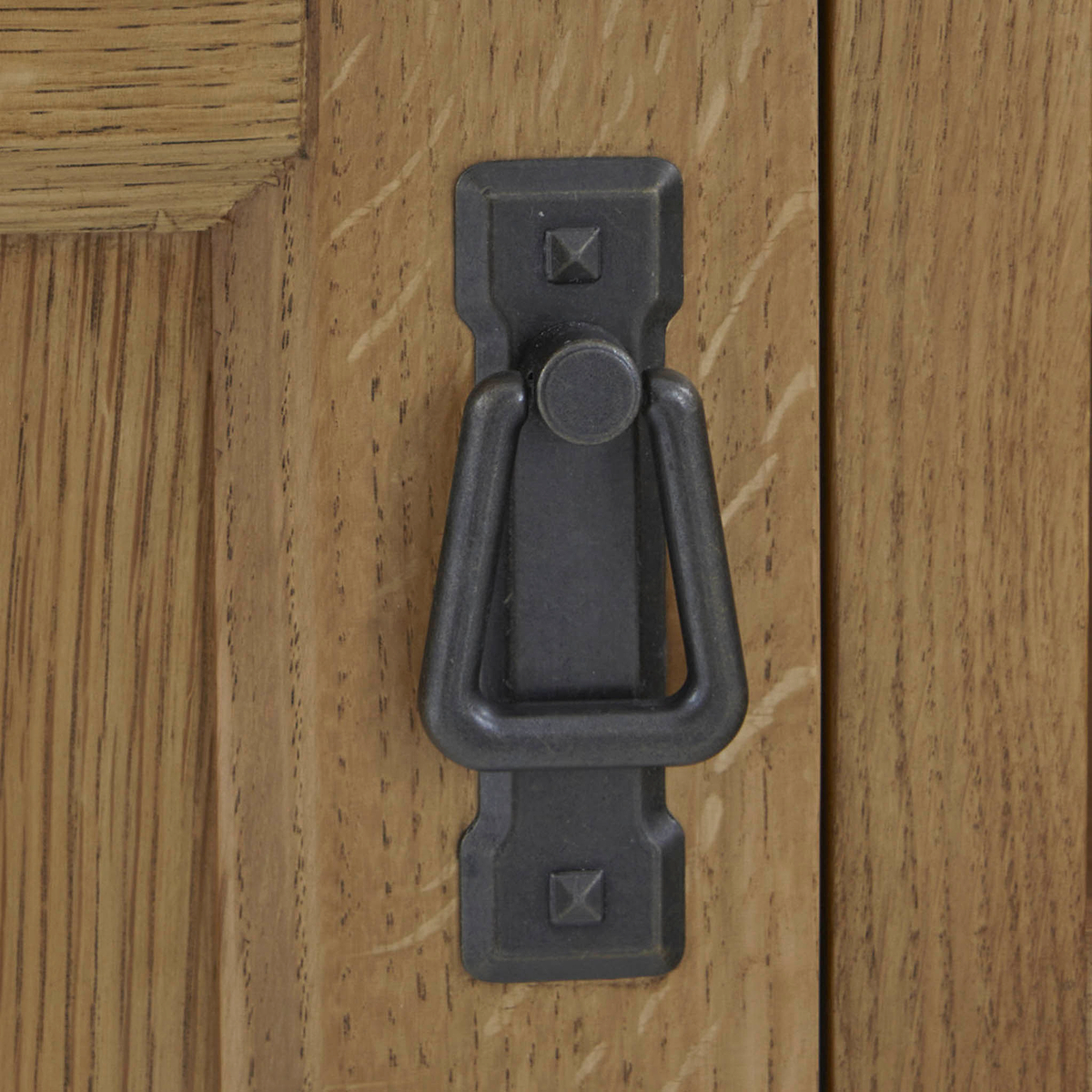 A dark metal door knocker is mounted on a light wooden door, featuring a simple, traditional design.
