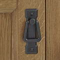 A black metal knocker affixed to a wooden door, providing a means for visitors to announce their presence.