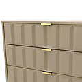A beige geometric-patterned dresser with gold handles partially opens one drawer, revealing a reflection on a glossy surface below.