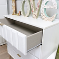 Decorative letters spelling "LOVE" atop a white shelf with an open drawer revealing a fabric-lined interior against a soft-hued backdrop.