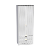 A tall white wardrobe with a textured design stands closed against a plain backdrop. The wardrobe features two doors and two lower drawers with golden handles.