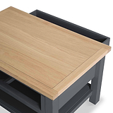 A rectangular wooden tabletop sits slanted on a black metal frame, suggesting an adjustable or convertible piece of furniture, depicted against a plain white background.