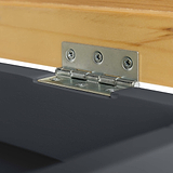 A metal hinge connects a light wooden panel to a black surface, illustrating a junction of materials possibly within a piece of furniture.