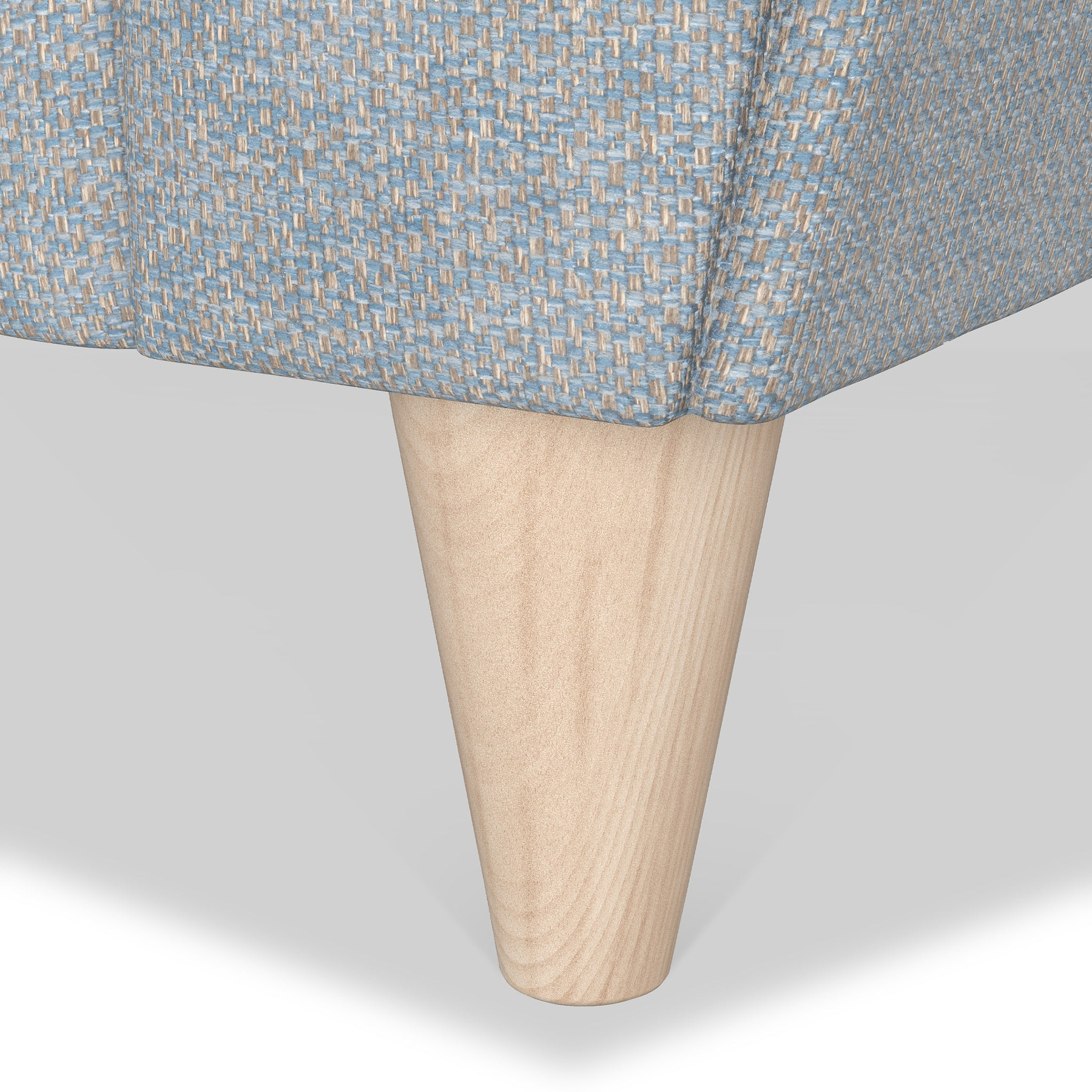A wooden leg of a piece of furniture, likely a couch or chair, with a textured blue and white fabric cover above it, set against a plain white background.